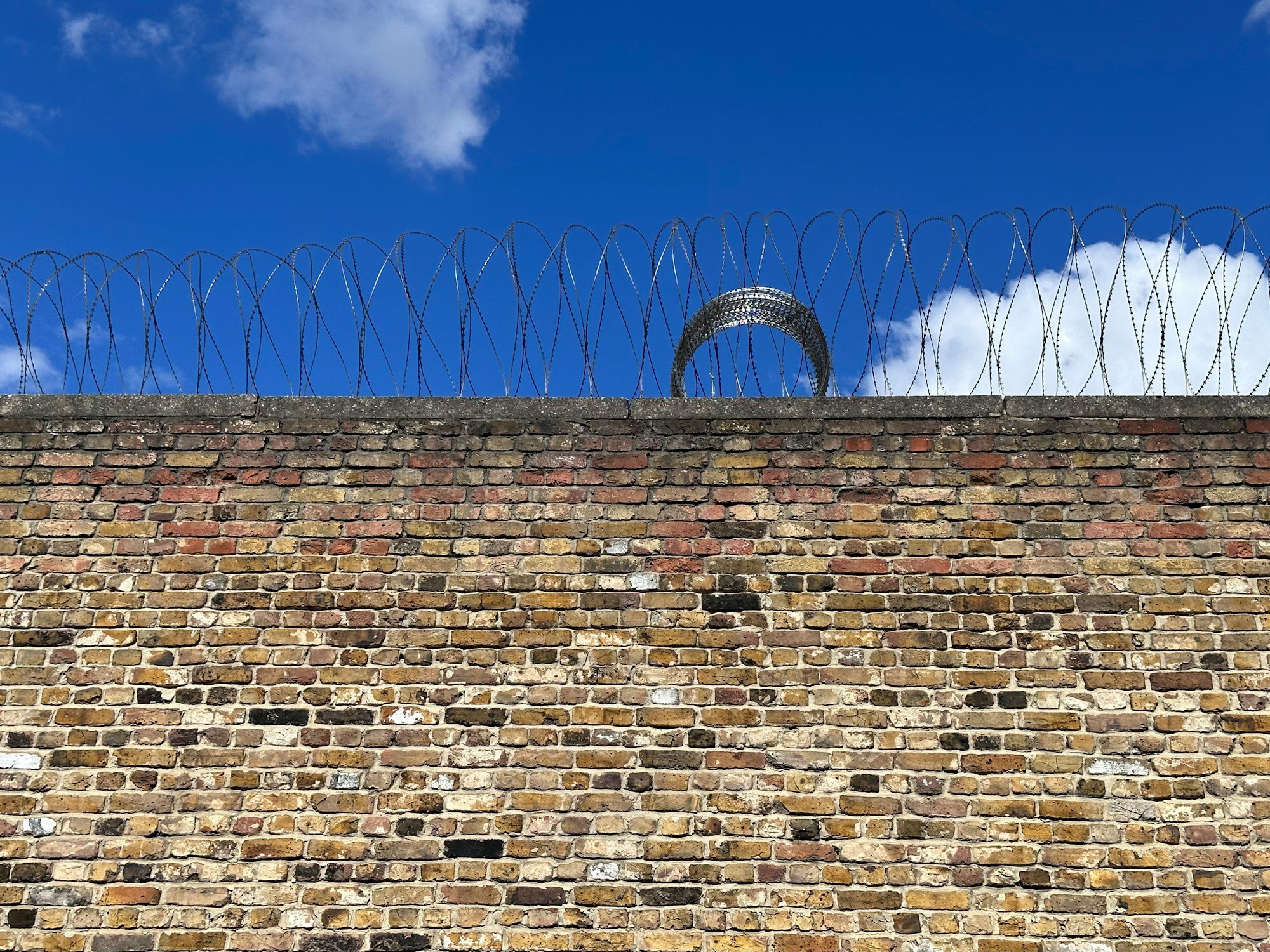 a brick wall with barbed wire on top of it a brick wall with barbed wire on top of it